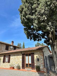 una casa de piedra con un árbol delante en Casa il Cipresso, en Castelnuovo Berardenga