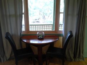 uma mesa e duas cadeiras em frente a uma janela em Blue House at Mountainside Wines em Mount Cole