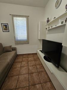 een woonkamer met een bank en een flatscreen-tv bij Nika Holiday Home in Casteldaccia