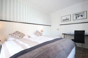 a white bedroom with a bed and a desk at Haus Anna - Wohnung 3 in Wangerooge