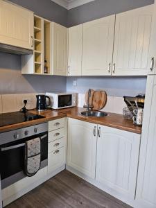 uma cozinha com armários brancos e um lavatório em One Bedroom flat sittingbourne em Kent