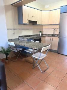 eine Küche mit einem Tisch und Stühlen sowie einem Kühlschrank in der Unterkunft Apartamento en El Médano con piscina y garaje in El Médano
