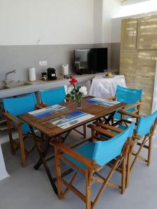 a dining room with a table and blue chairs at Blue Waves Suite Mykonos in Kalafatis