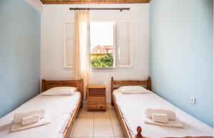 two beds in a room with a window at The Grapevine Rooms in Poros