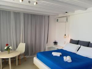 a bedroom with a blue bed and a table at Blue Waves Suite Mykonos in Kalafatis