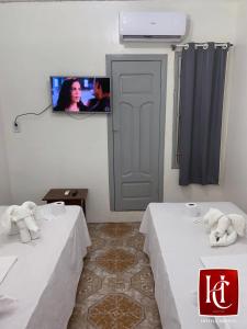 2 Betten in einem Zimmer mit einem TV an der Wand in der Unterkunft Hotel Central Abaetetuba in Abaetetuba