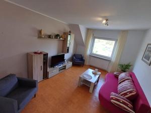 salon z fioletową kanapą i telewizorem w obiekcie Ferienhaus Urban mit Garage w mieście Wimbach