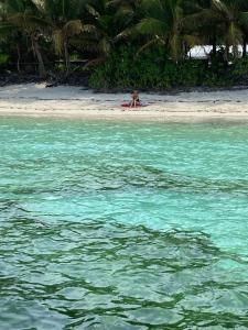 une personne se posant sur une plage dans l'eau dans l'établissement Voyager Retreat Homestay, à Nanuya Lailai