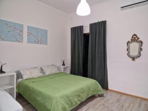 a bedroom with a green bed and a mirror at Milner Flats in Sliema