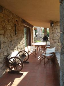 a patio with a table and chairs and a stone wall at Villa Stella in Costa Paradiso