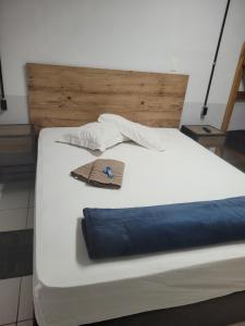 ein weißes Bett mit einem Kopfteil aus Holz und einem Hut darauf in der Unterkunft Pousada Central in Bragança Paulista