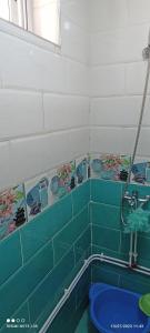 a bathroom with green tiled walls and a blue tub at terrasses des tamaris in 'Aïn Taya