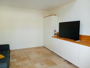 sala de estar con TV de pantalla plana en una pared blanca en Chambre de charme, en Cuers
