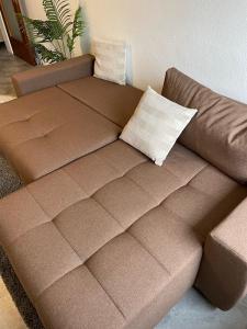 a brown couch with two pillows on top of it at RuhrGEbietsquartier - Gemütliche Wohnung in Gelsenkirchen-Buer in Gelsenkirchen