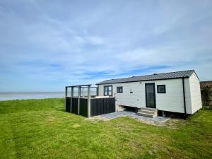 a tiny house on the beach with the ocean in the background at Chalet direct aan Waddenzee in Westerland