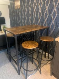a table and two stools in a room with a wall at Cozy Diamond Apartment in Bletchingdon