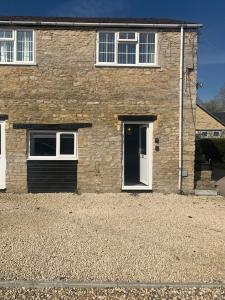 a brick house with a white door and two windows at Cozy Diamond Apartment in Bletchingdon