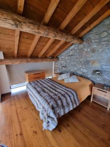 a bed in a room with a stone wall at Orri de Planès in Planès