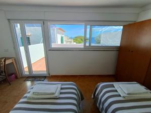 twee bedden in een kamer met een groot raam bij A Casicedda in Lipari