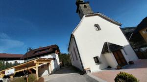 una iglesia blanca con campanario y un edificio en Himmlisch Urlauben in Pichl en Schladming
