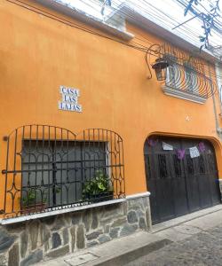 Guest House Casa Las Lajas في أنتيغوا غواتيمالا: مبنى برتقالي بأبواب سوداء ونباتات عليه