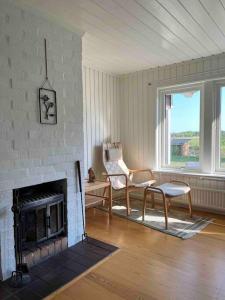 a living room with a fireplace and a chair at Stuga i Björkäng med havsutsikt! in Tvååker
