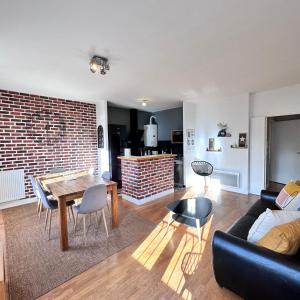 a living room with a table and a brick wall at Cosy Apartment Carré Elysée Serris in Serris