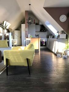 a living room with a yellow couch and a kitchen at Light flow stylish attic house. m. balcony in Rastatt