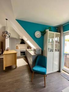 a kitchen with a blue wall and a blue chair at Light flow stylish attic house. m. balcony in Rastatt