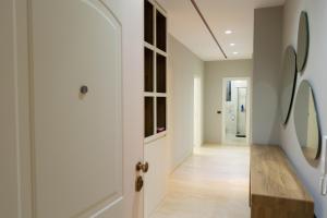 a hallway with white walls and a door with a mirror at Luxury Lungomare apartament in Vlorë