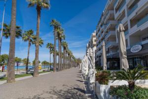 a sidewalk lined with palm trees next to a building at Luxury Lungomare apartament in Vlorë