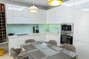 a kitchen with white cabinets and a glass table and chairs at Luxury Lungomare apartament in Vlorë