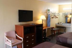 a hotel room with a bed and a desk with a television at Woodstream Inn in Hogansville