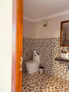 a bathroom with a toilet and a tiled floor at Villa Pich Boutique in Kampot
