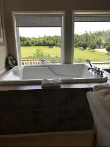 a bath tub in a bathroom with a window at Pacific Rim Guest Lodge - Adults Only in Ucluelet