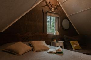 una camera da letto con un letto con un libro e una finestra di Pirtelė dviem a Kulionys