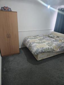 a bedroom with a bed and a wooden cabinet at Thorogood house in Dagenham