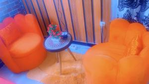 a living room with orange chairs and a vase with a plant at La fierté in Ziguinchor