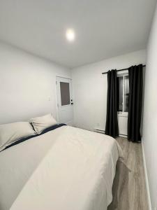 - une chambre avec un lit blanc et une fenêtre dans l'établissement Appartement 1 chambre - 201, à Montréal