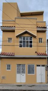 een geel huis met witte deuren en ramen bij Departamento Martha in Valle de Santiago