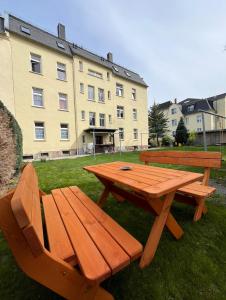 una mesa de picnic de madera y un banco en el césped en 1 Raum Wohnung in ruhiger Lage, en Limbach - Oberfrohna