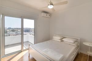 ein weißes Schlafzimmer mit einem Bett und einem Balkon in der Unterkunft Limanaki Beach Aparment in Larnaka