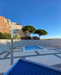 een zwembad op een patio met een hek en bomen bij STUDIO VUE PORT PISCINE PARKING in Cap d'Agde