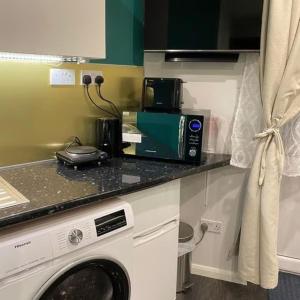 eine Küche mit einer Mikrowelle und einer Waschmaschine in der Unterkunft Vika Residence Deluxe Apartments Wednesbury Holiday Resort in Wednesbury