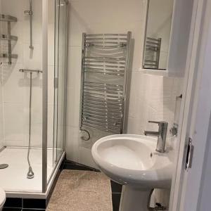 een witte badkamer met een wastafel en een douche bij Vika Residence Deluxe Apartments Wednesbury Holiday Resort in Wednesbury