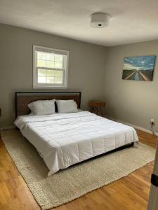 a bedroom with a large white bed with a window at Spacious Midtown Ranch- 10 min to Wrightsville in Wilmington