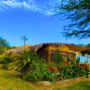una casa con tetto di paglia, fiori e piante di Fundo El Cortarrama a Talara