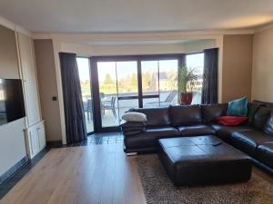 uma sala de estar com um sofá de couro e uma mesa em Kapstertje em Grimbergen