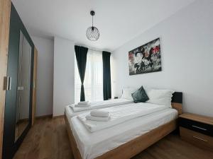 une chambre avec un grand lit avec des draps blancs dans l'établissement Sunset view Armoniei Apartament, à Timişoara