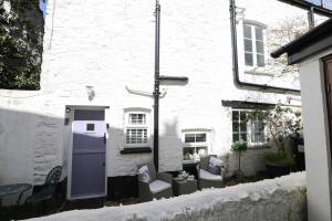 a white building with two chairs and a purple door at Ferndale Cottage in Lynmouth